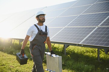 Indian man in uniform on solar farm. Competent energy engineer controlling work of photovoltaic...