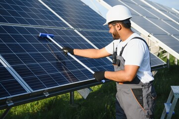 Indian handyman cleaning solar panels form dust and dirt