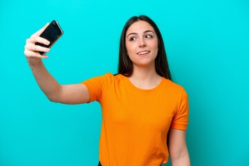 Naklejka premium Young caucasian woman isolated on blue background making a selfie