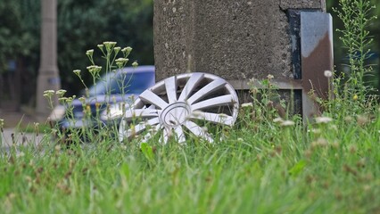 Missing Hub Cap from Car Wheel Cover Left on Roadside Grass Lawn by Busy City Street