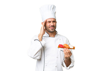 Young caucasian chef holding a sushi over isolated background with headache