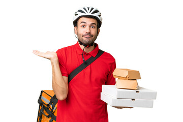 Young handsome caucasian man with thermal backpack and holding takeaway food over isolated background having doubts while raising hands