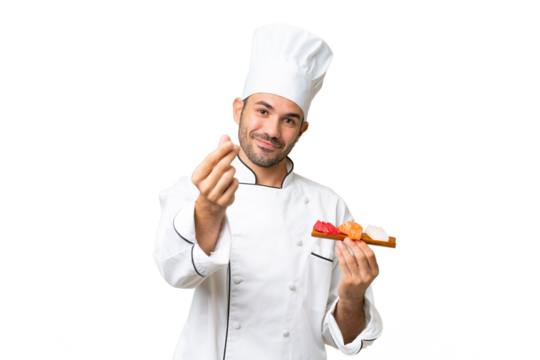Young caucasian chef holding a sushi over isolated background making money gesture