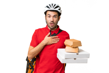 Young handsome caucasian man with thermal backpack and holding takeaway food over isolated background surprised and shocked while looking right