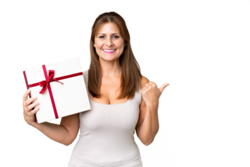 Middle age caucasian woman holding a gift over isolated background pointing to the side to present a product