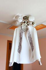 An embroidered men's shirt hangs on the chandelier. A hanger with the inscription 