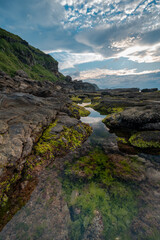 Sunset time in the coastline of Keelung city, under the ocean and rocks full of seaweed, in Taiwan.