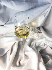 White wine chardonnay sauvignon blanc glass on a white textile background. Top view.