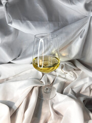 White wine chardonnay sauvignon blanc glass on a white textile background. Top view.