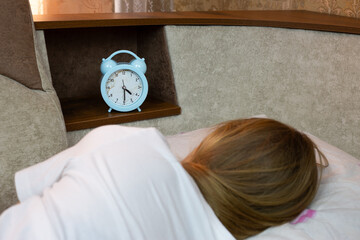Girl sleeping on sofa next to alarm clock on shelf, healthy daytime sleep for human rest, health...