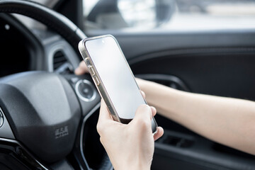 Young man using smart phone mobile phone in car. Close up view. While driving and using a mobile phone, it may cause serious accidents to fellow road users and other road users.