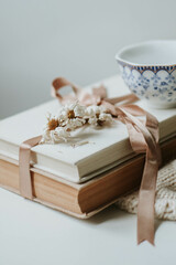 Cozy autumn day. Reading books. Elegant still life: warm beige sweater, books, flowers and vintage cup