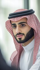 A man with a beard and a red and white scarf on his head