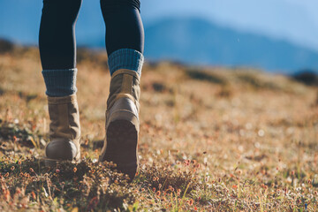 Hiker legs wearing leather boots hiking on high altitude mountain top