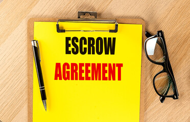 ESCROW AGREEMENT text on yellow paper on clipboard with pen and glasses
