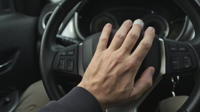 Angry male driver honking the car horn during traffic jam, closeup of hand on steering wheel