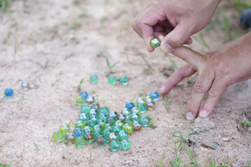 Closeup hand holds round small marble balls to play games. Concept, traditional childen play toy....