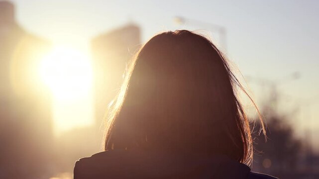 Rear view of female person standing alone on city street in autumn morning