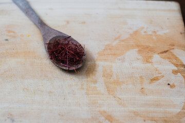 Wooden spoon full of red Saffron in cutting board, herbal tea, healthy drinks.