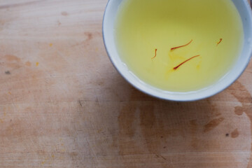 A saffron water mix in white cup in wooden cutting board, herbal tea, healthy drinks.