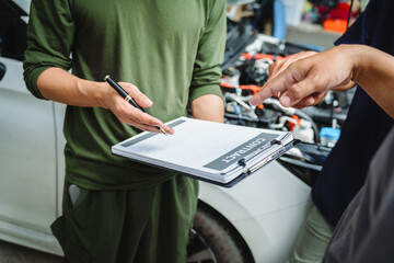 Three Asian men discussing car insurance policies with adjuster. They review details such as...