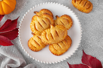 Pumpkin mini pies or hand pies with glass of coffee on a stone background. Traditional autumn dessert for Halloween and Thanksgiving. Copy space