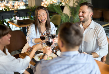 Group of happy business people enjoying in dinner at a restaurant and toasting with red wine.
