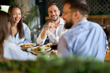 Group of cheerful entrepreneurs talking while enjoying in their lunch at a restaurant. 