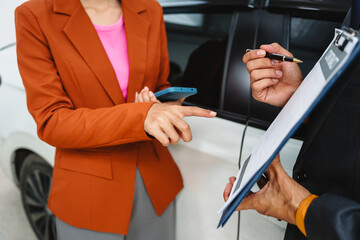 Car seller agent signs a car insurance agreement with salesman. The document outlines vehicle policy, premium, rental terms, with contract paper finalized using car insurance claim mobile phone.