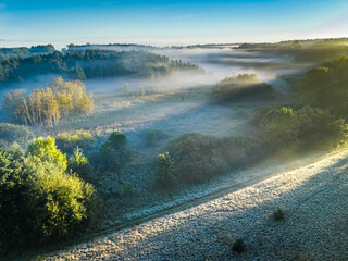 Aerial view of foggy valley at sunrise and sun beam.