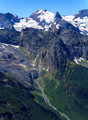 View of a small river with a waterfall flowing out of a mountain glacier