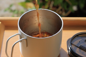 Pouring tea in cup. Healthy hot drink. Black tea drink. Cup Of Tea Closeup Over Nature Green Background