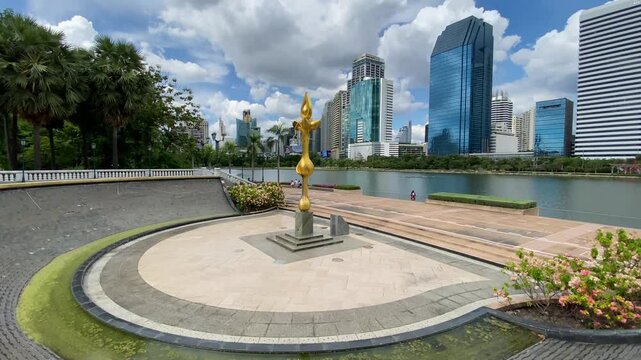 Monument in front of Ratchada lake in Benjakitti Park, also known as Benchakitti, during a sunny weekend in Bangkok, Thailand.