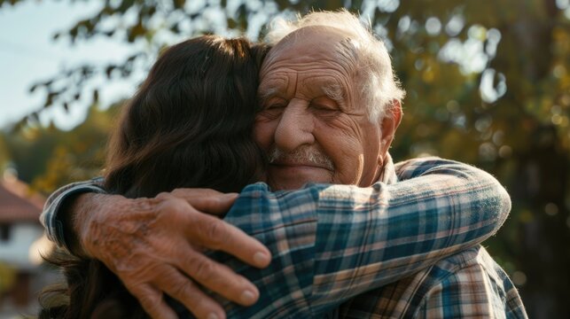 Elderly man hugging woman in park - Powered by Adobe