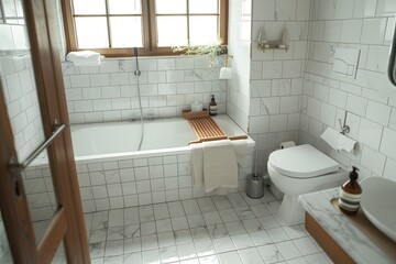 A photo of the interior bathroom with white tiles, a bathtub and small toilet in a Scandinavian style, with a wooden tray on top. An open glass door next to which there is no shampoo bottle.