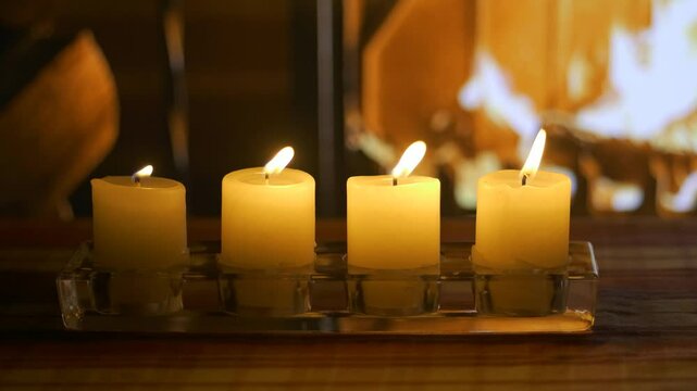 Fourth Advent. Four candles on the background of a burning Christmas fireplace. Christmas cozy setting