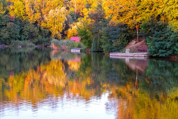 Fototapeta premium Colorful autumn trees and wooden house reflection in the water