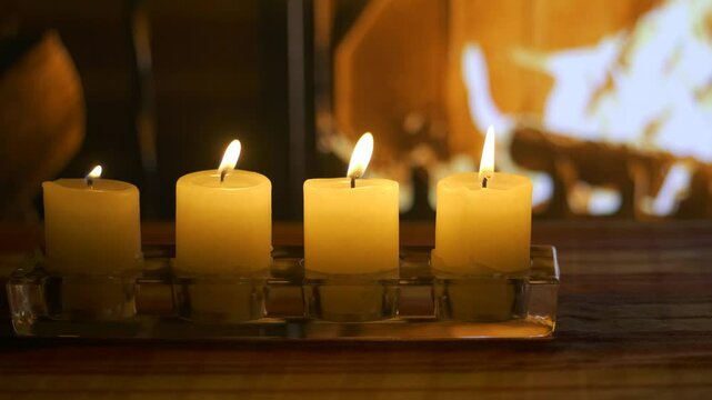 Fourth Advent. Four candles on the background of a burning Christmas fireplace. Christmas cozy setting