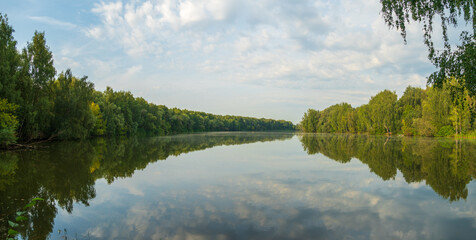Reflection of trees in the lake. Panoramic view of the banks of the river bay