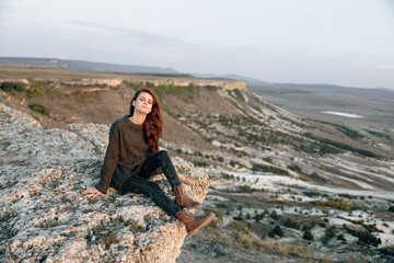 Serene woman sitting on rock admiring majestic mountain view during golden sunset