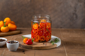 Fermented preserved vegetarian food concept. Mini colorful bell pepper glass jars over rustic kitchen table. Canned food concept.