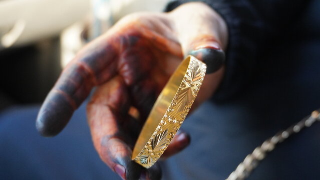 My mother's hand examines the shiny gold bracelet.
