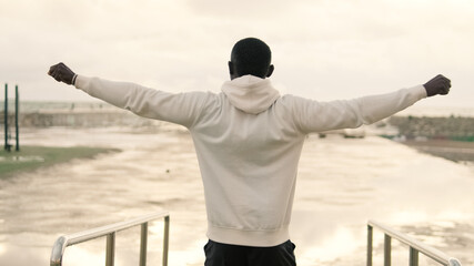 Back view of a man in sportswear looking out to sea, motivation moment