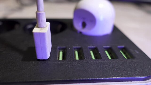 Male hand plugging cables into a power outlet. A versatile modern extension cord with sockets and usb ports.