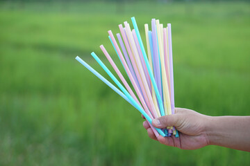 Close up hand holds colorful plastic drinking straws tubes.  Concept single use equipment for...