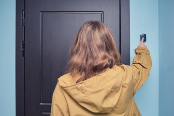 Person in yellow jacket ringing doorbell. Rear view photograph of a person pressing a doorbell...