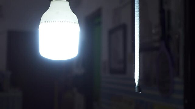 A hand pulls the switch cord and turning on the light in a room at the night. Energy saving LED bulbs