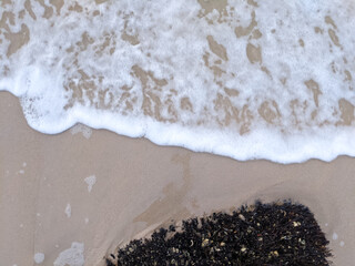 The white foam results from the waves breaking up on the shore
