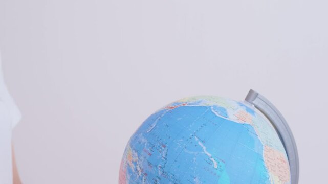 A child pointing to Japan on a globe.  地球儀にある日本を指す子供