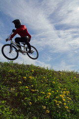 Obraz premium Low angle view of a silhouetted bmx racer against a cloudy sky.